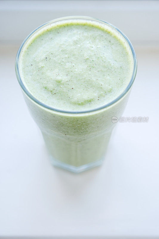 一杯绿色奶昔含有奇异果、芒果、羽衣甘蓝叶、椰子和杏仁牛奶