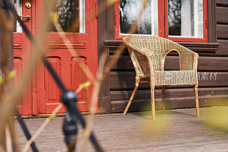 斯堪的那维亚风格的房子，木墙边阳台上的柳条扶手椅