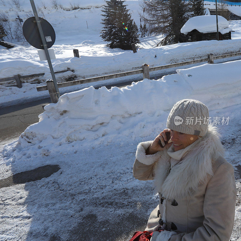 一个女人在下雪的街道上打电话。