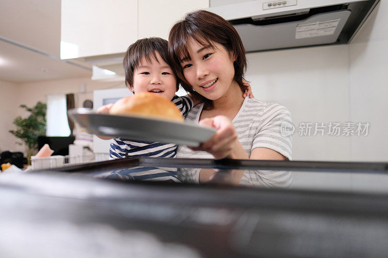 家庭主妇和她的孩子打开微波炉门