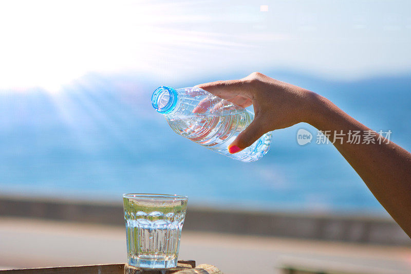 那只手正在把瓶子里的水倒在海滩上。