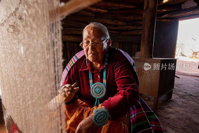 年迈的印第安纳瓦霍妇女正在霍根织布机上编织传统的部落毛毯