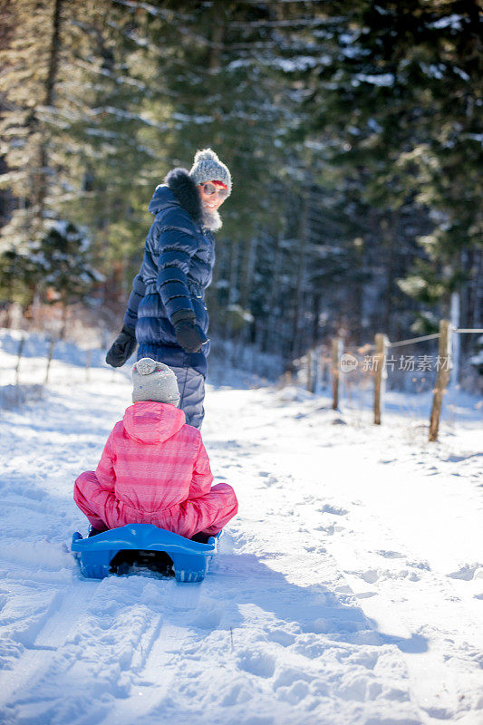 母亲和女儿在大自然中享受雪橇
