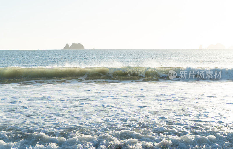 清晨的阳光透过新西兰海滩上的碎浪