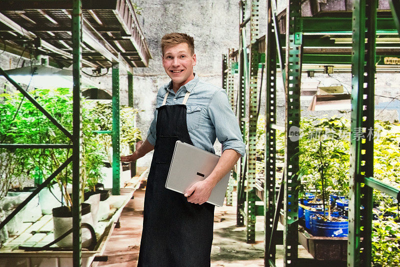 大麻店-一名男性员工正拿着一台笔记本电脑