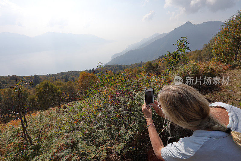 女人用手机拍山和湖