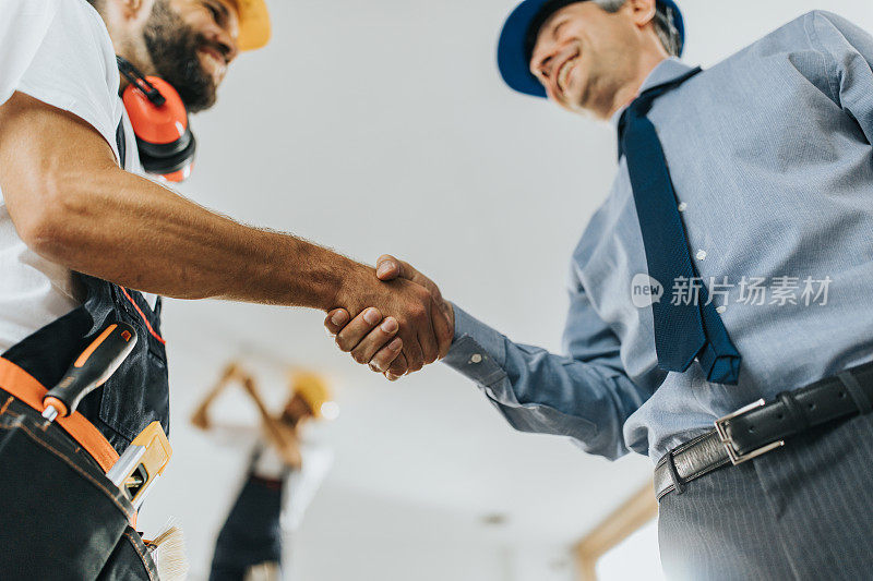 下面是建筑工地手工工人与建筑师握手的画面。