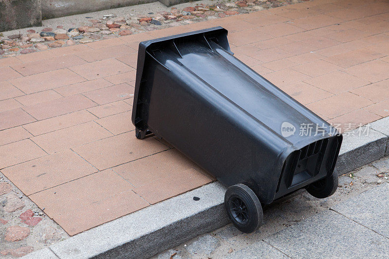黑色垃圾桶倒在人行道上