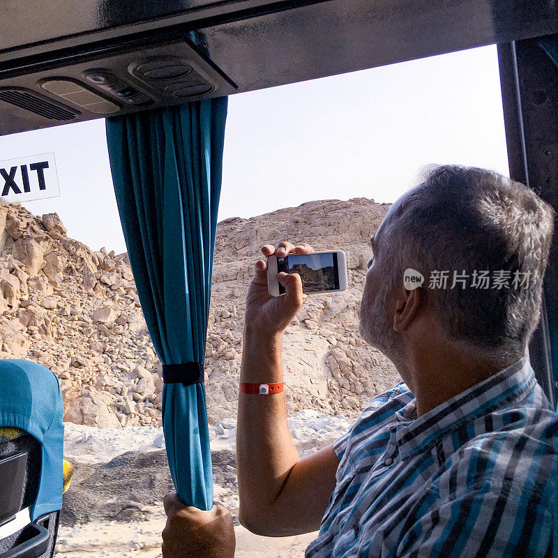 高级男子在沙漠中旅行时用手机拍照
