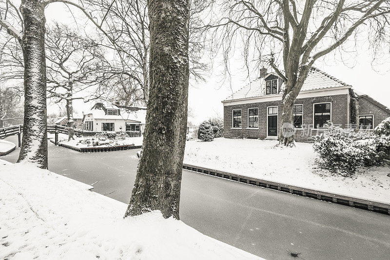 在一个寒冷但美丽而平静的冬天，Giethoorn村的运河和积雪