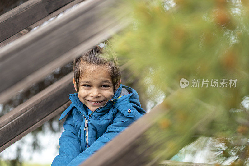 快乐的小男孩坐在木楼梯上