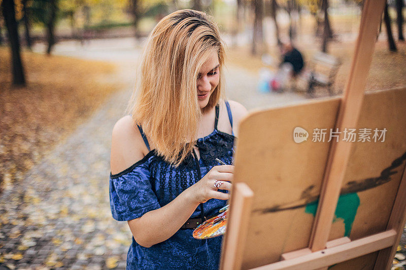 一位年轻的女艺术家正在大自然中作画