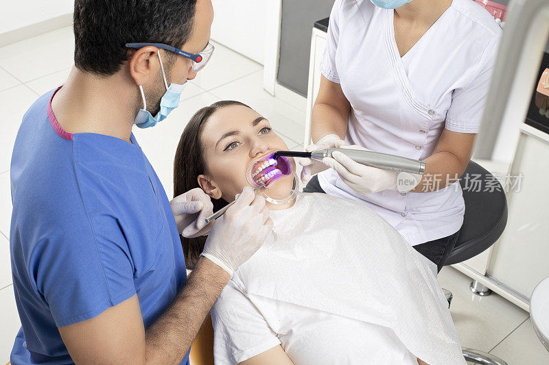 男牙医检查漂亮的年轻女子的牙齿