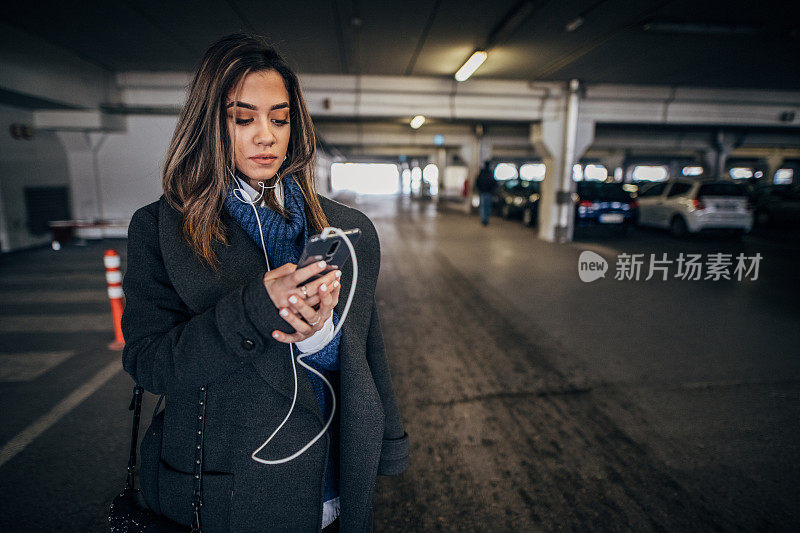 一个女人在地下车库用智能手机听音乐