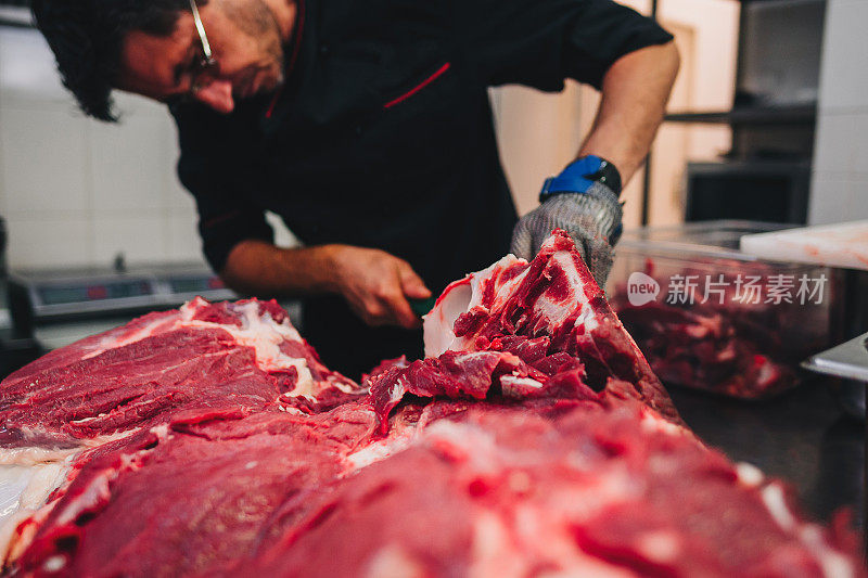 男屠夫在餐厅厨房用刀切生牛肉