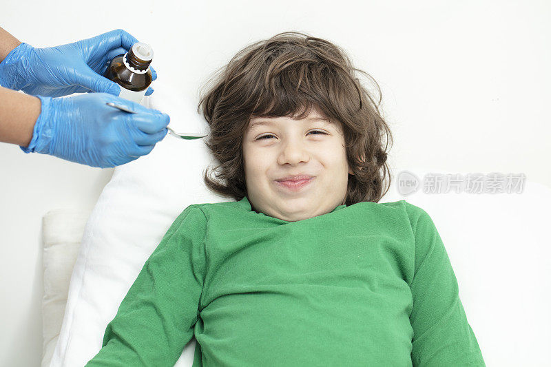 生病的小男孩从医生那里吃药水