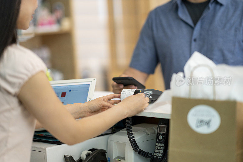 顾客在一家小型精品店用智能手机付款