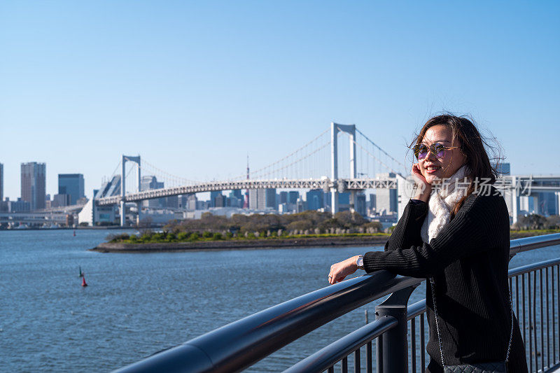 年轻的亚洲女人微笑着看着东京彩虹桥的景色