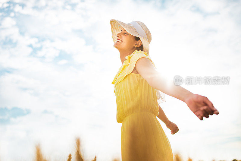 快乐的女人在麦田里呼吸新鲜空气