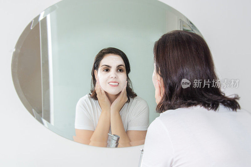 一个女人在镜子前擦面霜