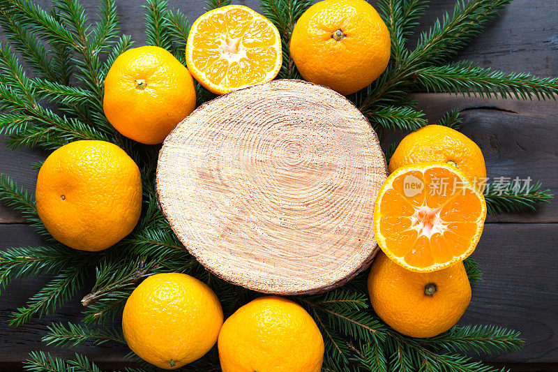 新年假日背景上剪圆的桔子树，活冷杉的树枝和金色的灯花环，用木制的空间为文字。柑橘的香气，一片片的橘子，圣诞的气息。框架