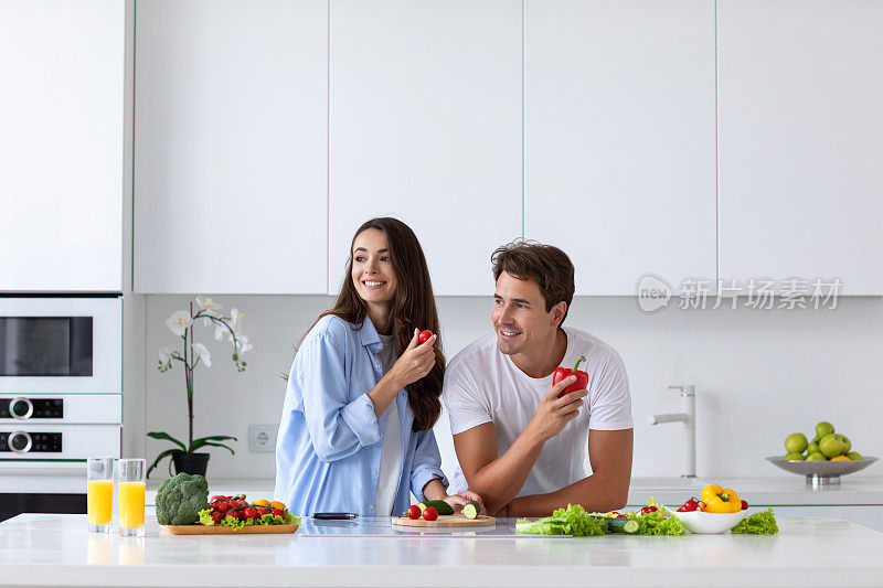 一对笑嘻嘻的夫妇在厨房准备健康沙拉。