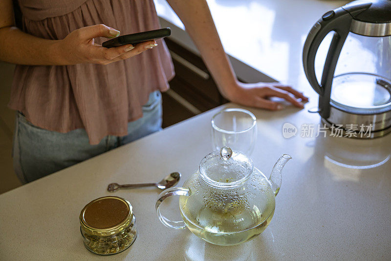 年轻女子正在准备一壶用干洋甘菊做的散叶洋甘菊茶。