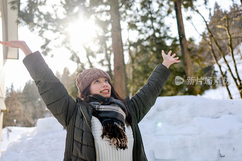 美丽的年轻女子在堆积的雪中举起双手