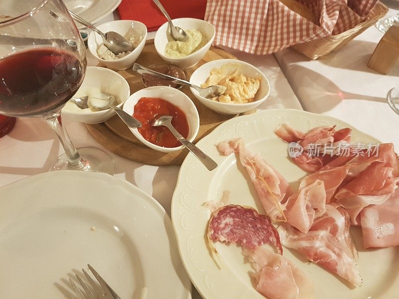各种意大利熟食和配餐盘与葡萄酒杯