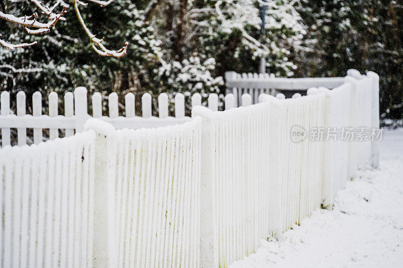 村子里房子外面的白色栅栏上覆盖着雪