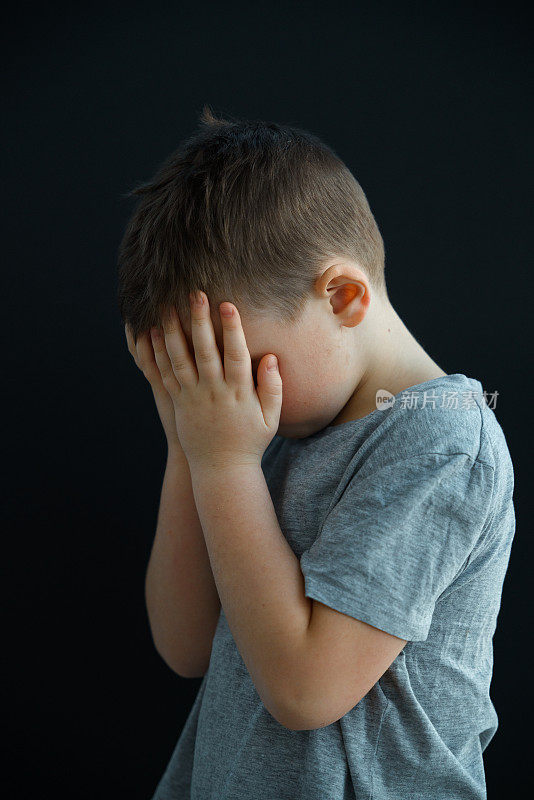 一个小男孩在哭，他用手捂着脸，也许有人冒犯了他，或者他的父母惩罚了他。