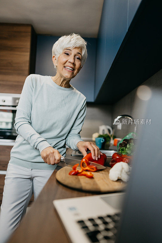 一位女士在厨房里用笔记本电脑打电话