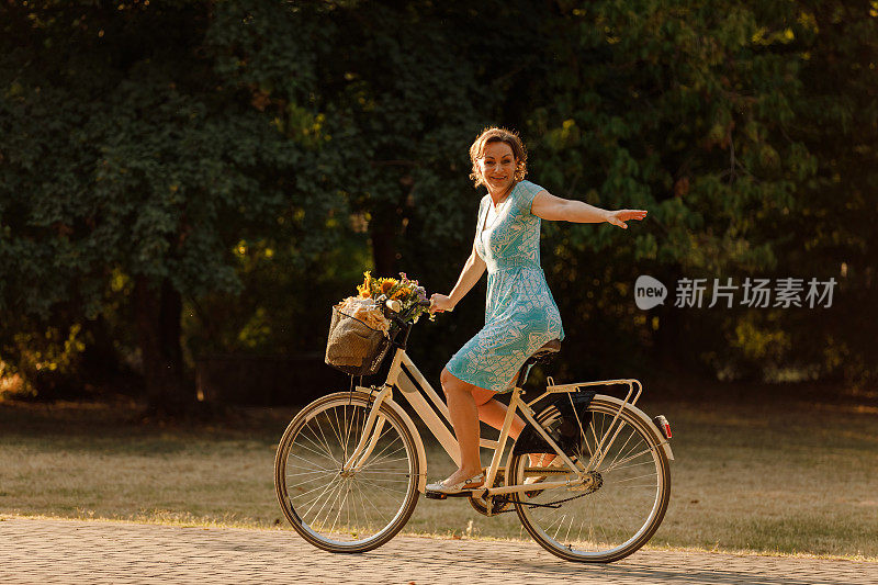 复制空间拍摄的女人骑着自行车，对着相机微笑，并给一个转向灯