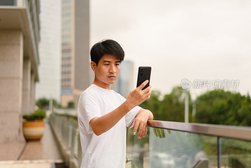 一名亚洲男子用智能手机自拍