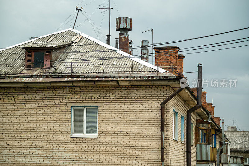 旧砖房的屋顶，有烟囱和很多电视天线