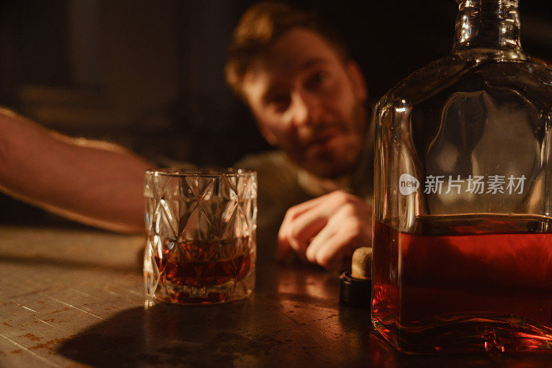 餐桌上一个喝着威士忌的醉汉的大气肖像。一张桌子上放着一杯威士忌的照片，背景是一个刚醒来的醉汉。
