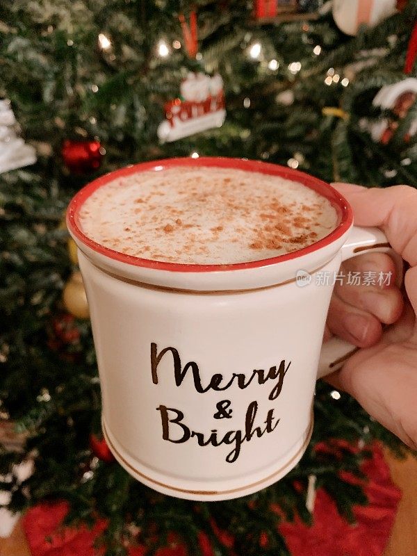 圣诞树前的咖啡杯里放着丰富的热拿铁和肉桂，2021年在家过一个舒适的圣诞节