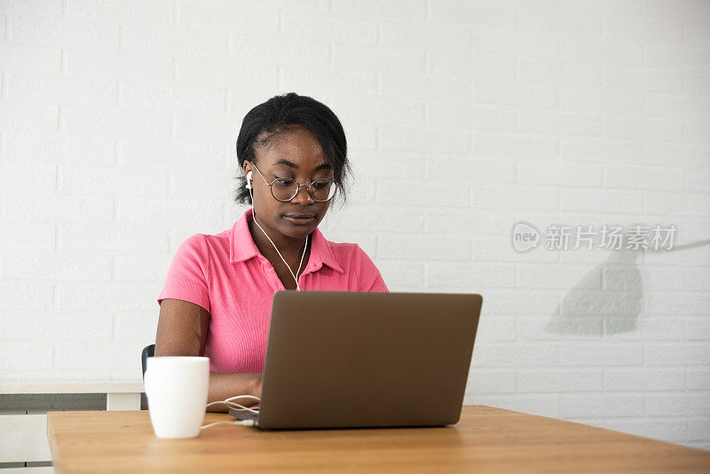 一名年轻的非洲裔美国妇女在笔记本电脑上打字，讲述她个人的负面经历，以及她对受雇同事和老板之间的商业关系的看法。