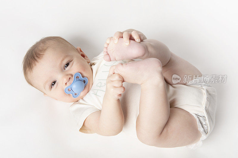 六个月大的男婴用奶嘴托住脚