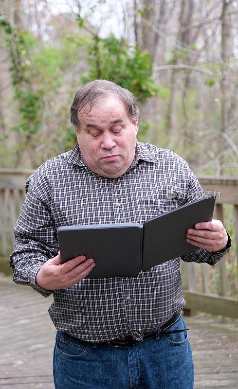 一位患有自闭症的成熟男性在户外手持数码平板电脑。