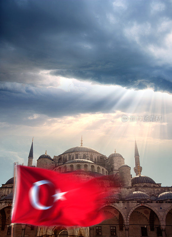 蓝色的清真寺和土耳其国旗在阳光下戏剧性的天空