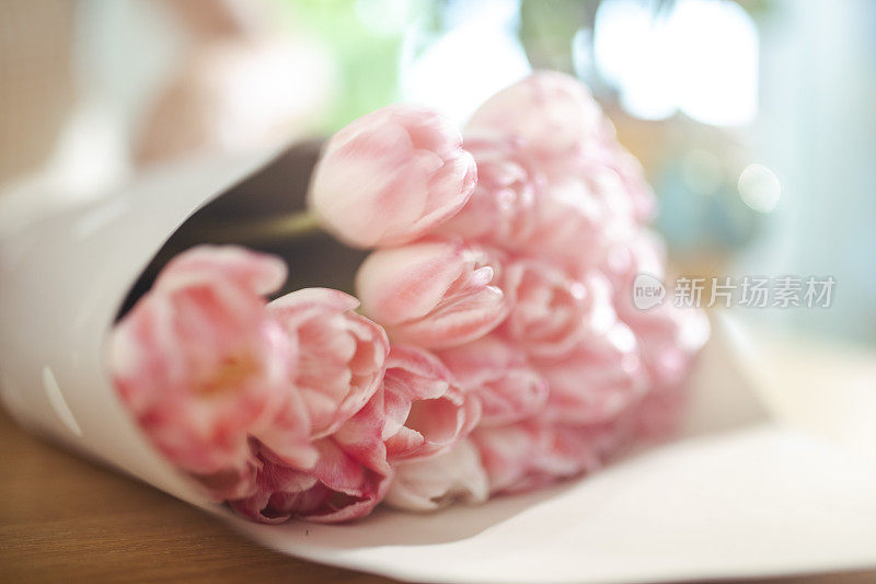 木桌上放着一束漂亮的粉红色郁金香。