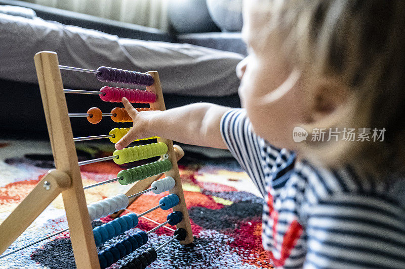 宝宝在家里玩木色珠算玩具。