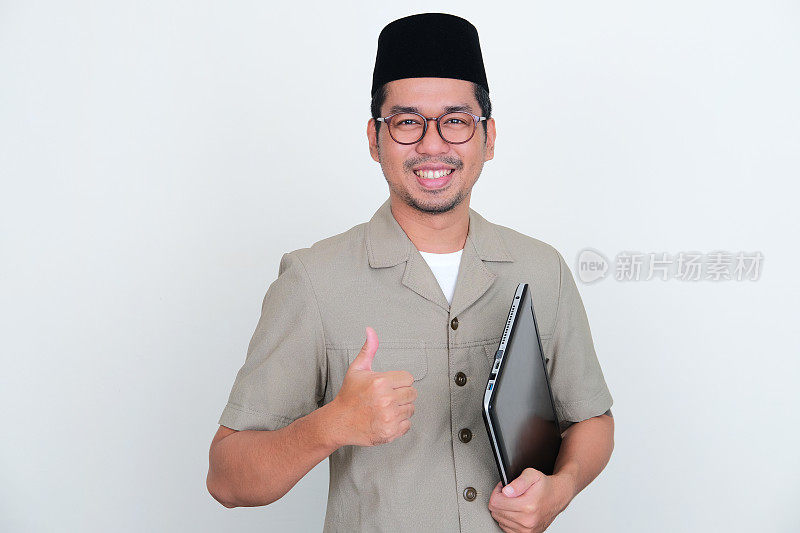 印尼老师对着镜头微笑，拿着笔记本电脑竖起大拇指