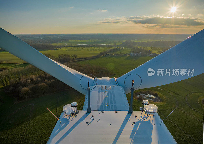 风力涡轮机机舱顶部的测量设备(超声波风速计)和航空灯，背景是对着太阳的田地。可再生能源。