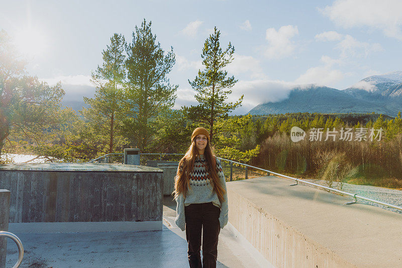 在挪威隆丹国家公园，背着双肩包的微笑女子凝视着山上的风景