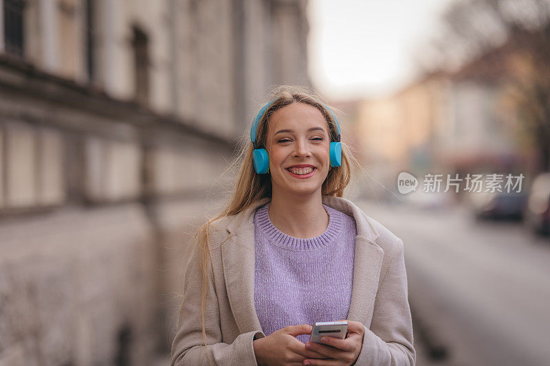 年轻自信的女人在街上听音乐的肖像