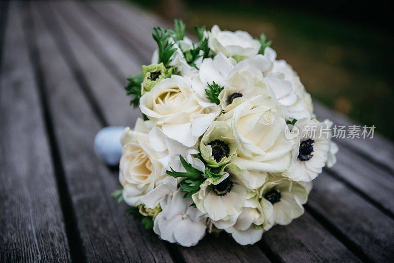 近距离拍摄的新娘白花花束在一个木凳在公园与模糊的背景