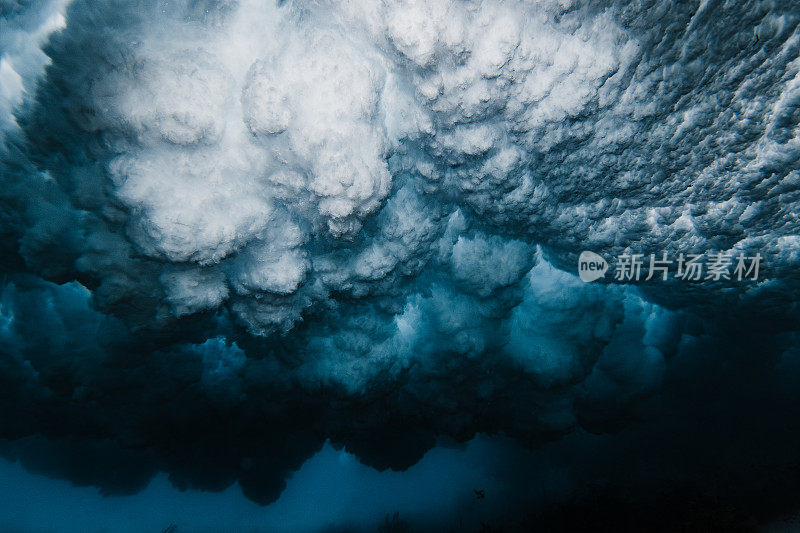 水下照片下的破碎波爆炸与高对比度分散的水模式使用闪光灯