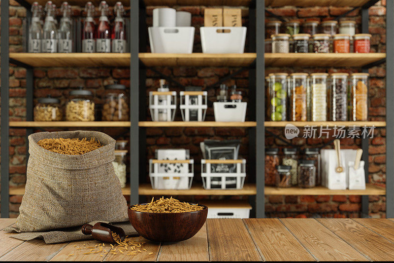 一袋谷物放在空木桌上，背景是模糊的食品储藏室和腌制食品